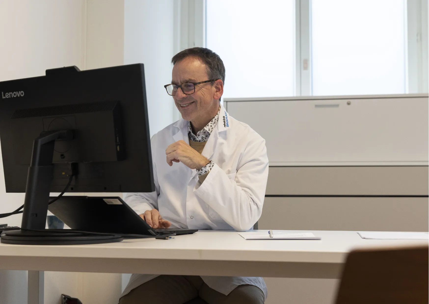 Dr. med. Wolfgang Fogel, Facharzt für Neurologie, am Schreibtisch im VITREA Rehazentrum Zürich Seefeld.
